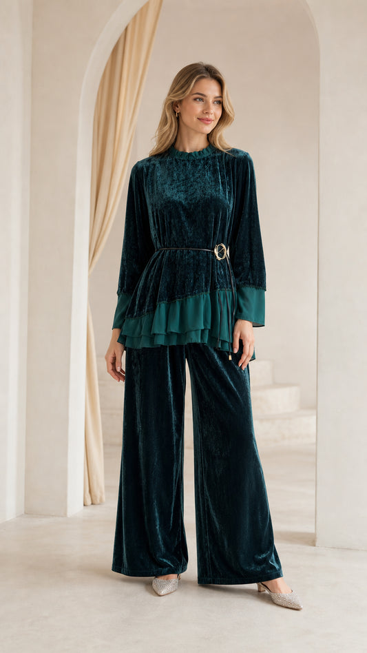 Front full view of woman wearing dark green crushed velvet two-piece pant set with belted ruffle top