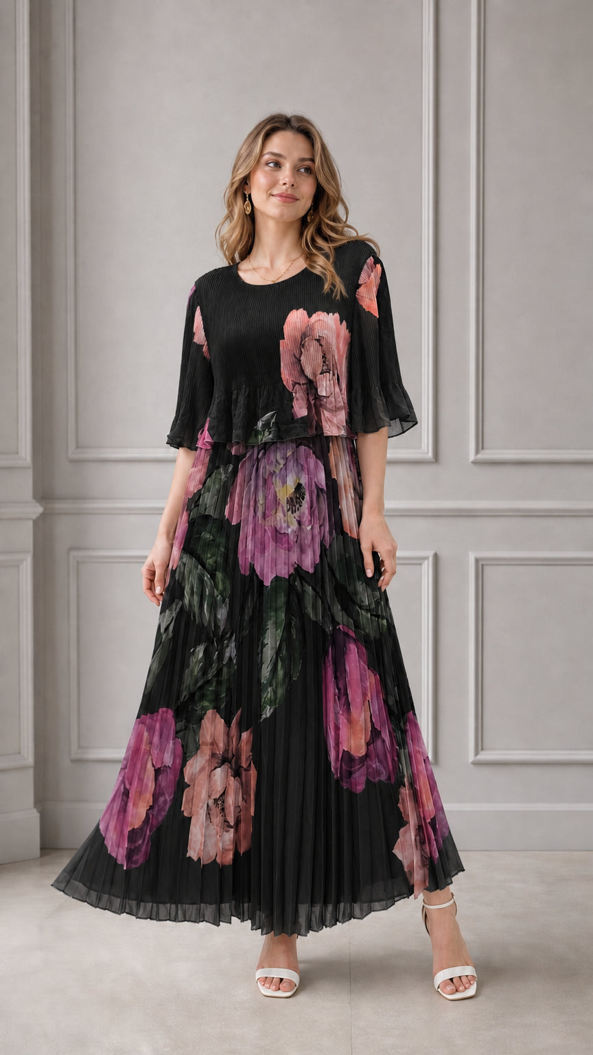 Model wearing black floral pleated maxi dress with capelet bodice