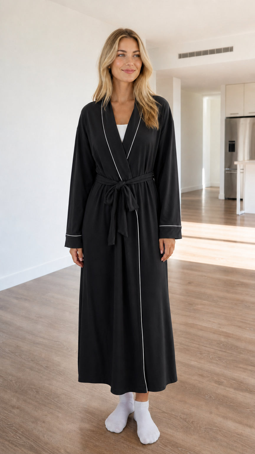 Front view of model wearing black long sleeve robe with white contrast piping