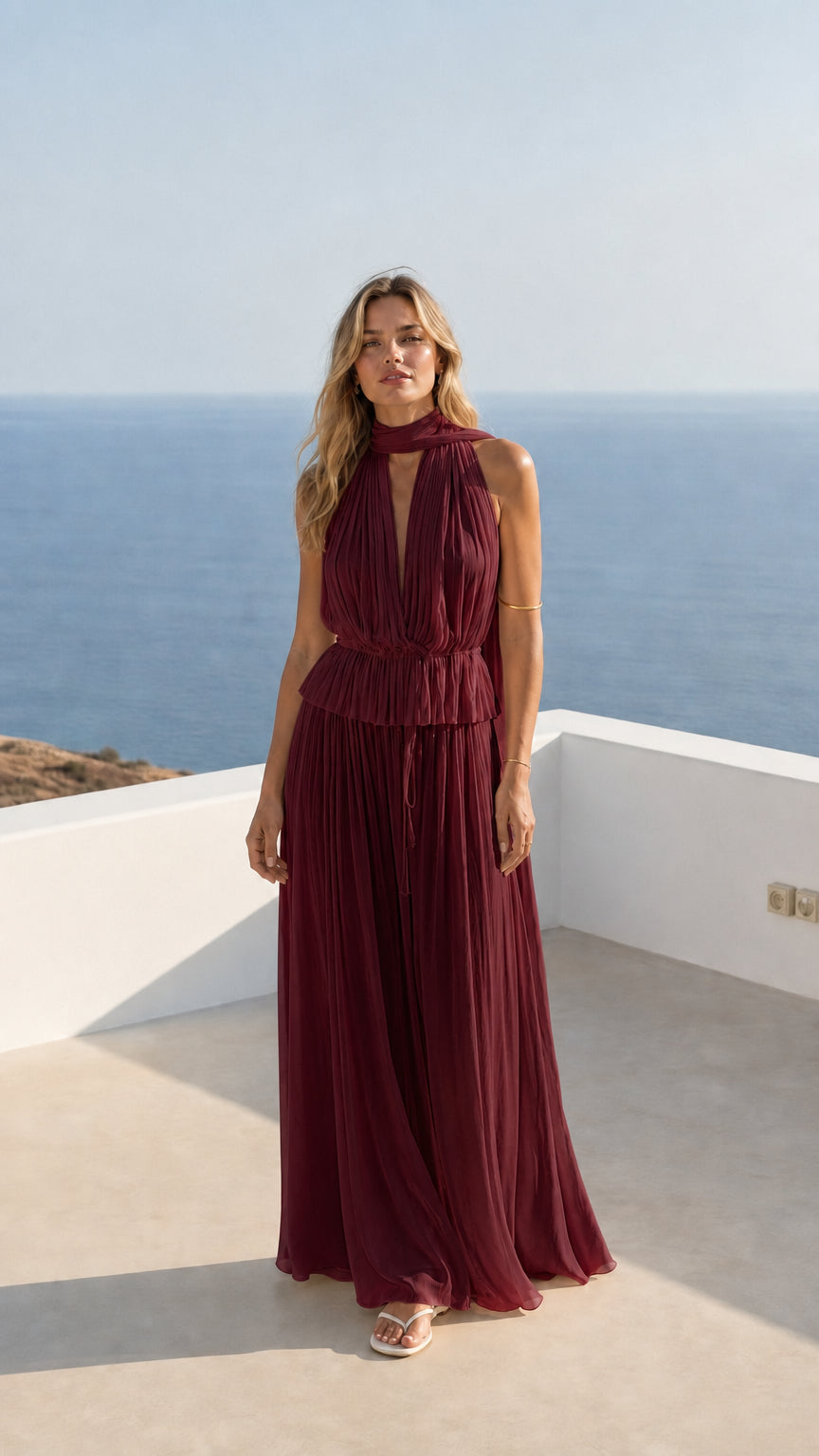 Woman wearing rich burgundy pleated halter maxi dress outdoors